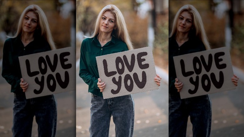 woman holding love you poster