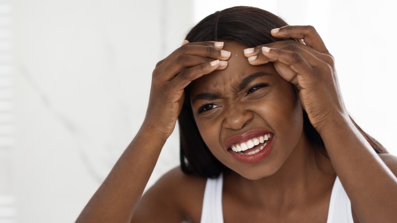 Black woman popping a pimple 