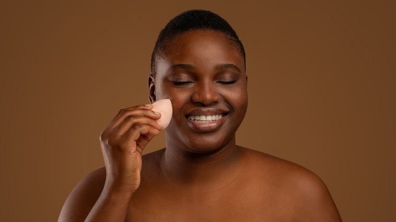 Black woman putting on makeup