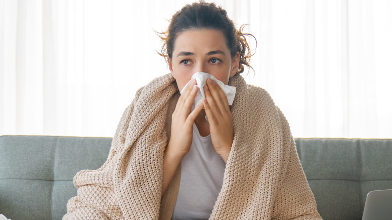 sick woman blowing nose