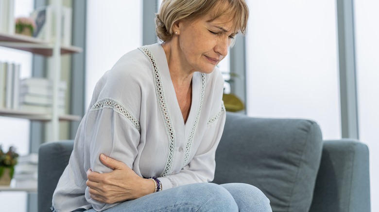 woman holds abdomen in pain