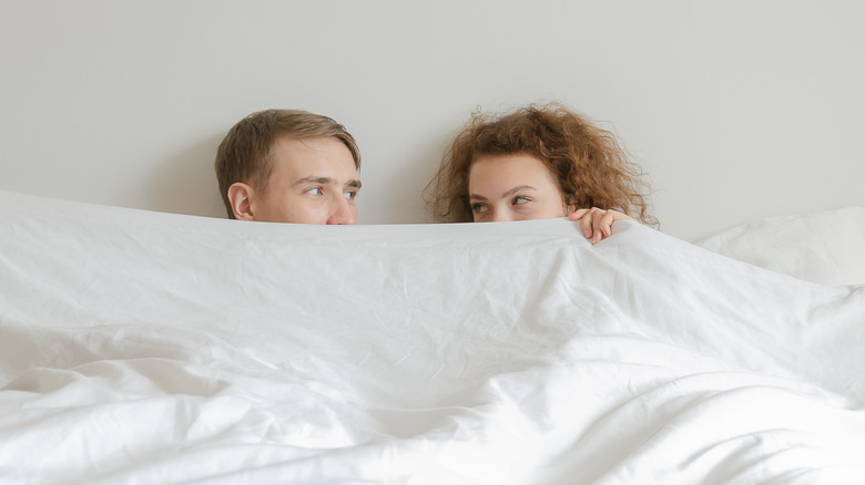 couple intimate in bed smiling with their eyes