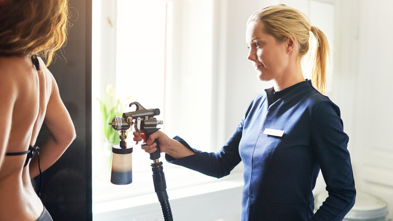 woman using spray tan gun 