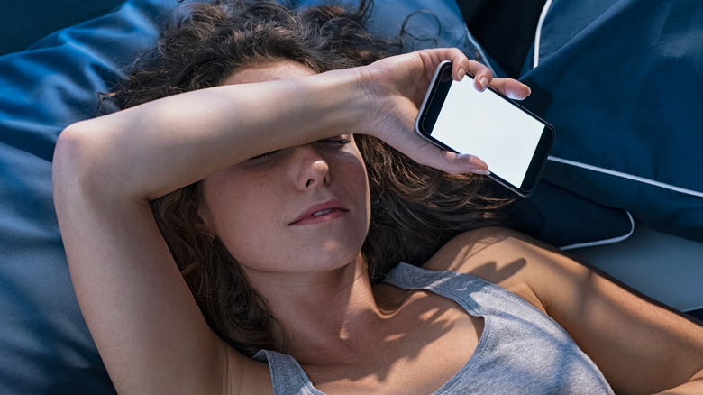 Woman lying in bed with smartphone