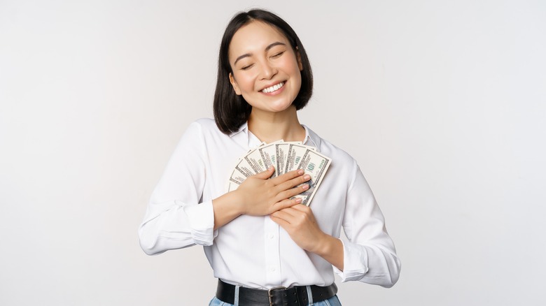 Woman smiling, holding cash