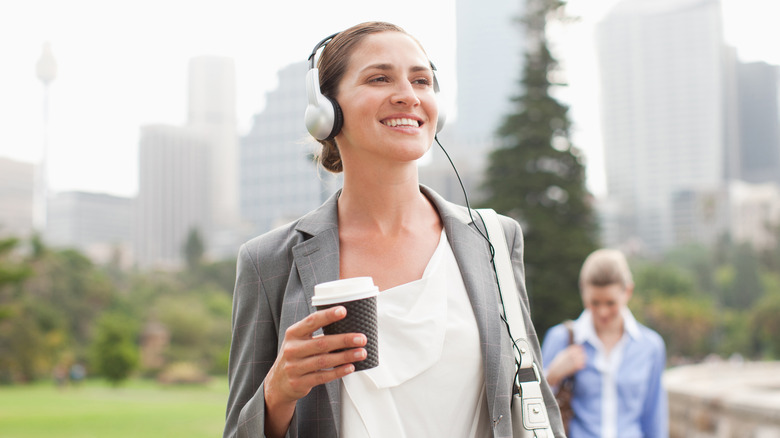 Woman smiling, wearing headphones outdoors