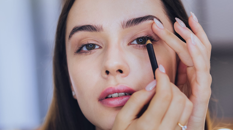 woman adding eyeliner to eyes