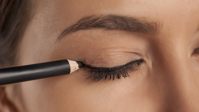 woman applying eyeliner pencil