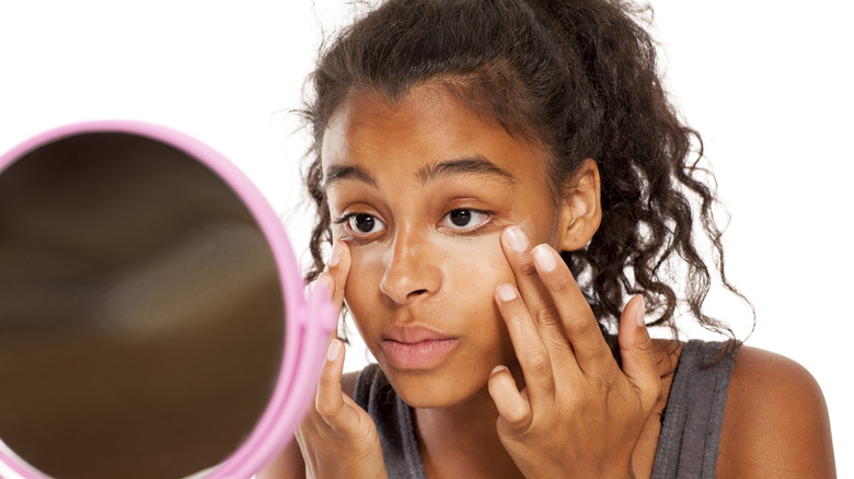 Woman applying concealer to under eyes