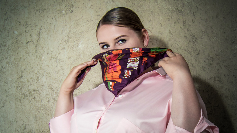 Woman holding scarf over face