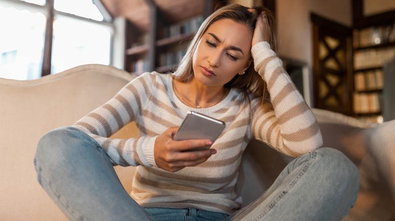 sad woman looking at phone 