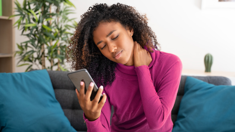 woman holding neck on phone 