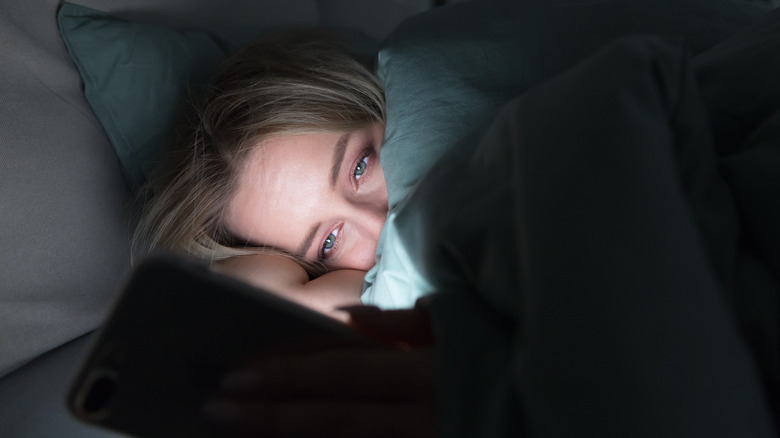 woman using phone in bed