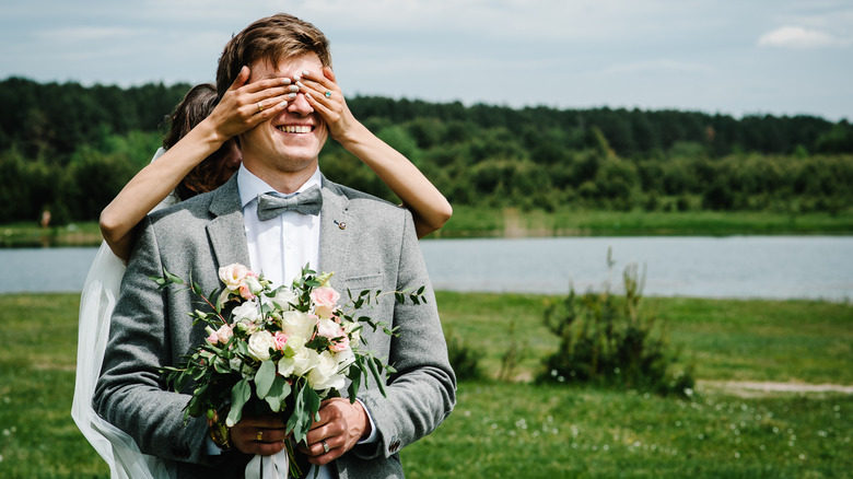 Bride covering the groom's eyes 