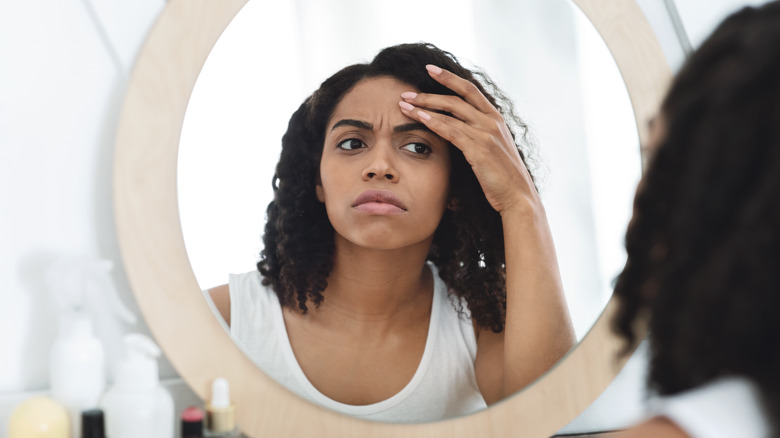 Woman examining face in mirror