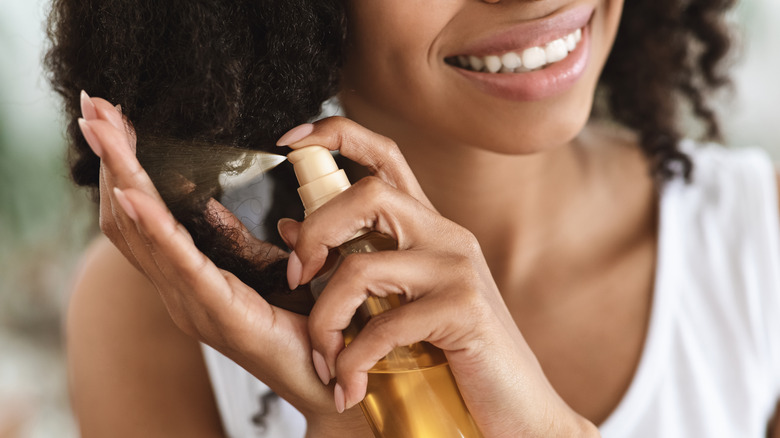 woman spraying hair with oil