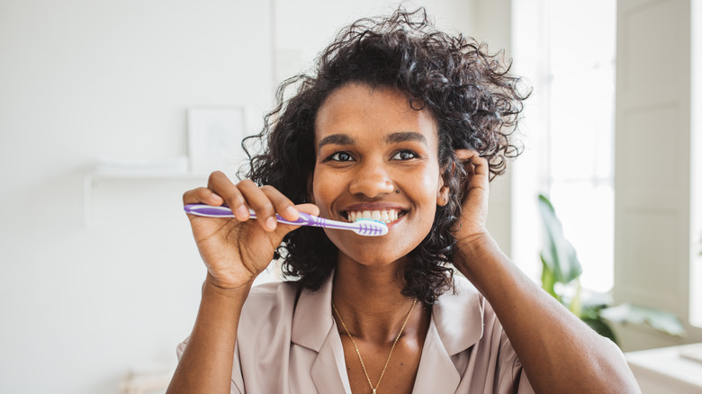 woman brushing teeth smiling