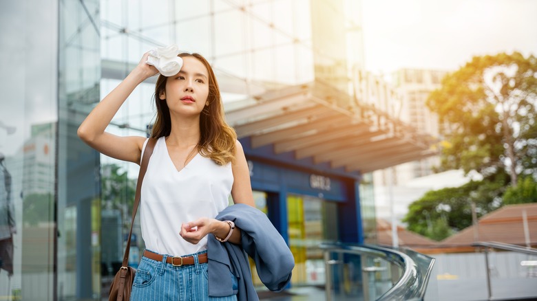 woman outside wiping forehead