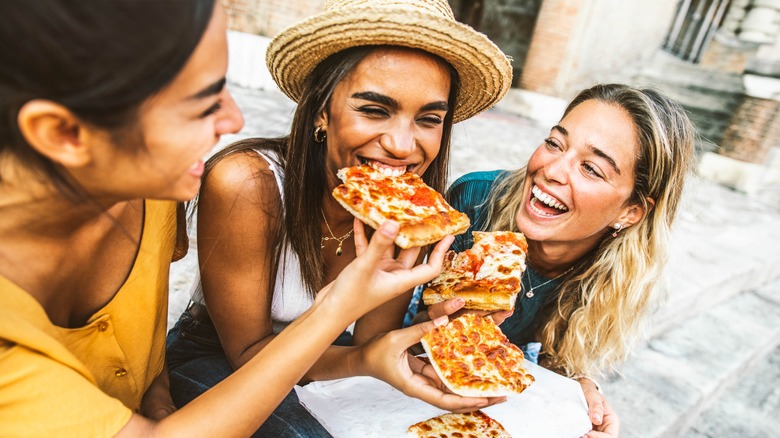 happy friends eating pizza
