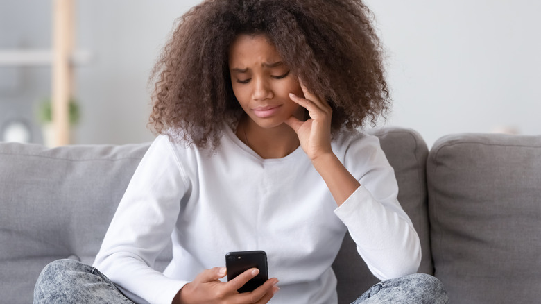 unhappy woman looking at her phone