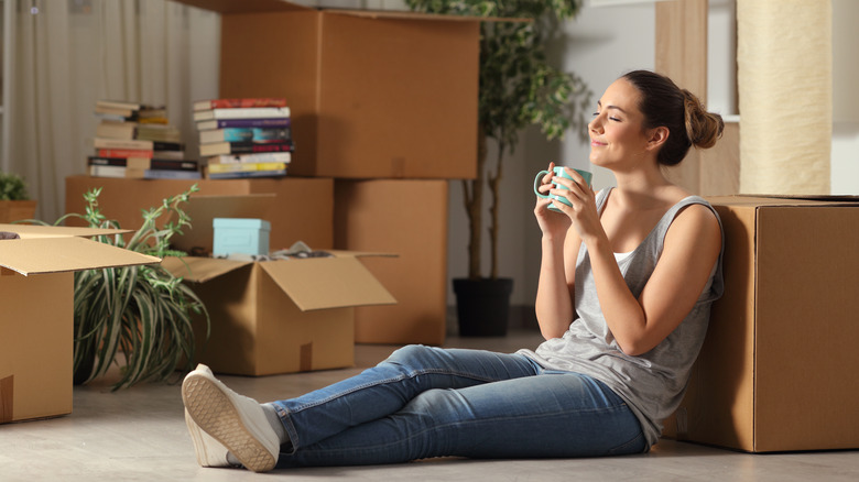 Woman enjoying hot beverage surrounded by boxes