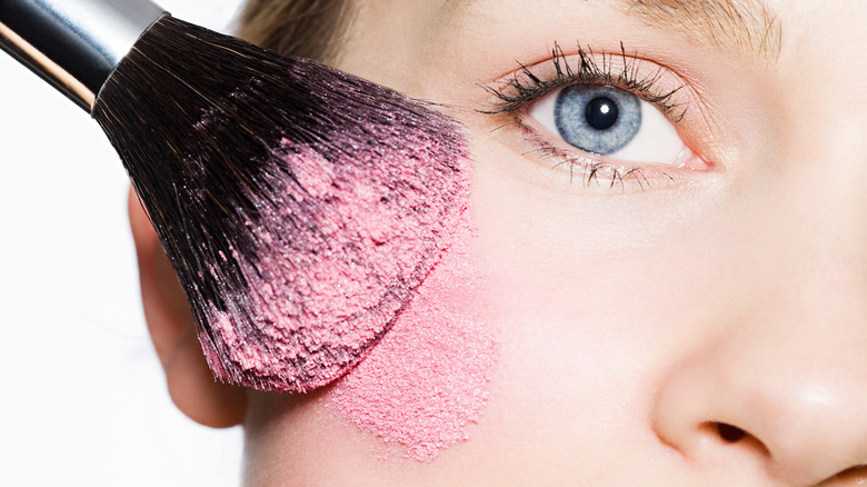 woman applying bright blush