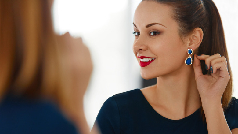 A woman putting on statement earrings