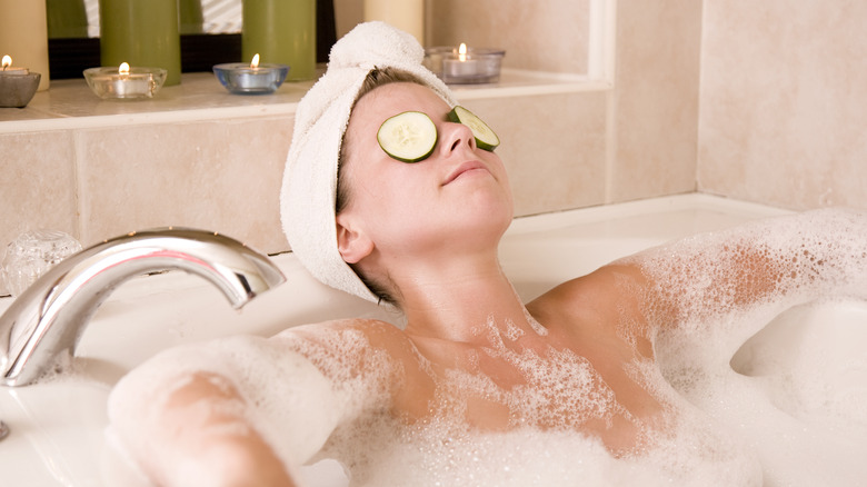 woman in bath with cucumbers on eyes