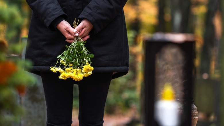 Woman holding flower at gravesite