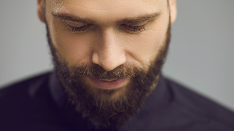 Bearded man looking down, humble