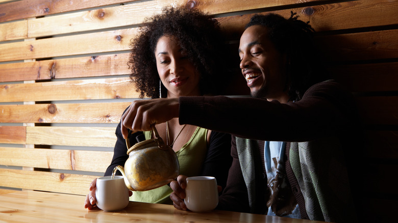 Man pours tea for woman