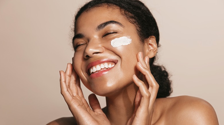 woman applying moisturizer to face