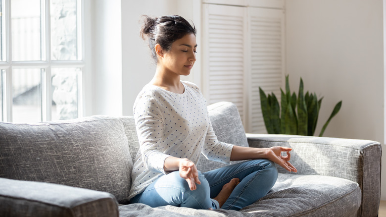 A woman meditating on a couch