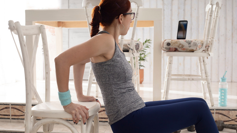 woman using dining chair to exercise