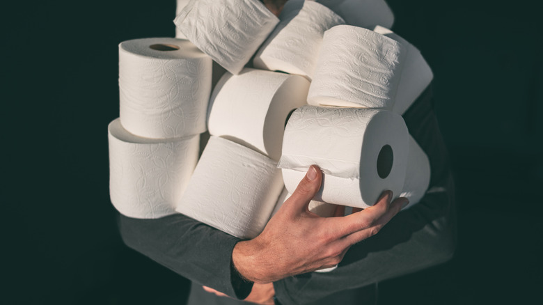 Arms holding toilet paper rolls