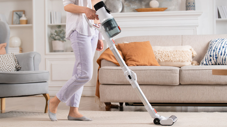 Woman vacuuming a rug at home