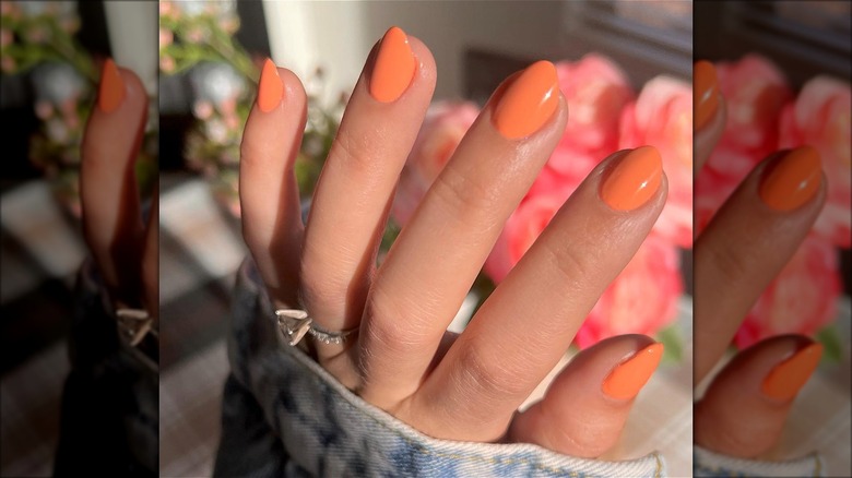 orange nail polish on fingers