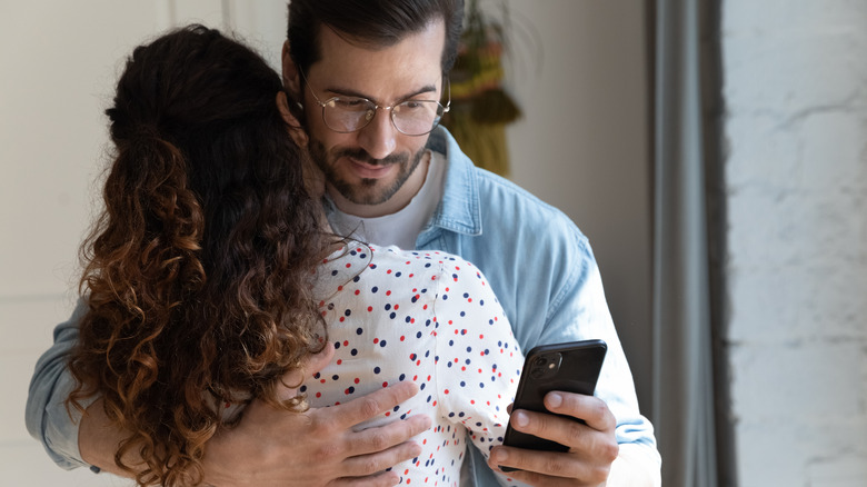 Man checking phone behind partner's back