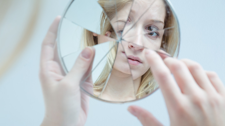 Insecure woman with broken mirror