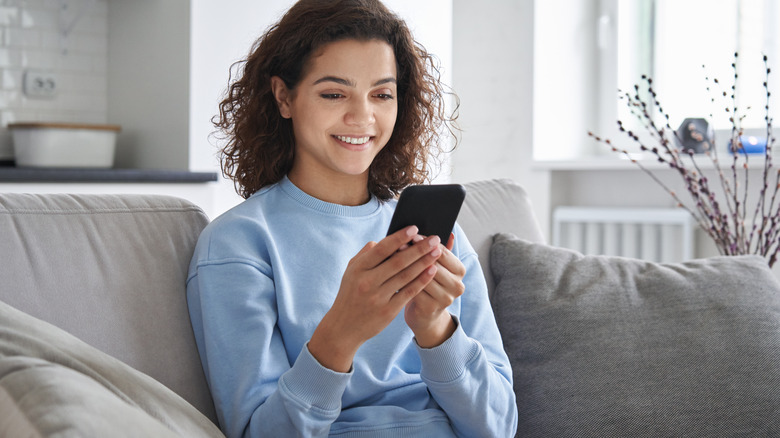 woman on her phone sitting on her couch