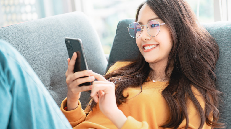 woman laying on a couch and on her phone