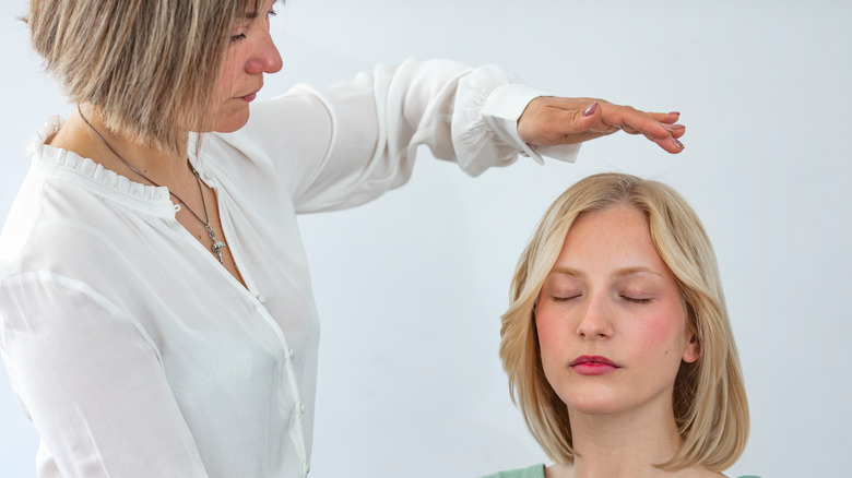 A woman performs reiki on another