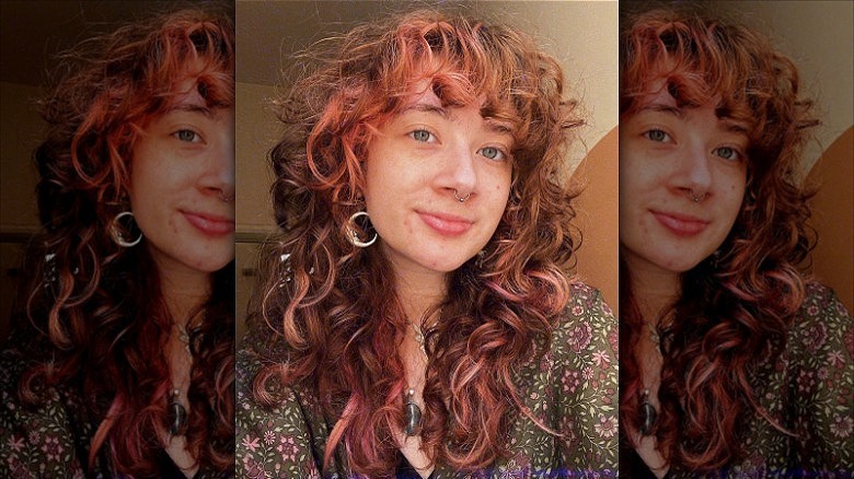 woman with peach highlights in brown curly hair