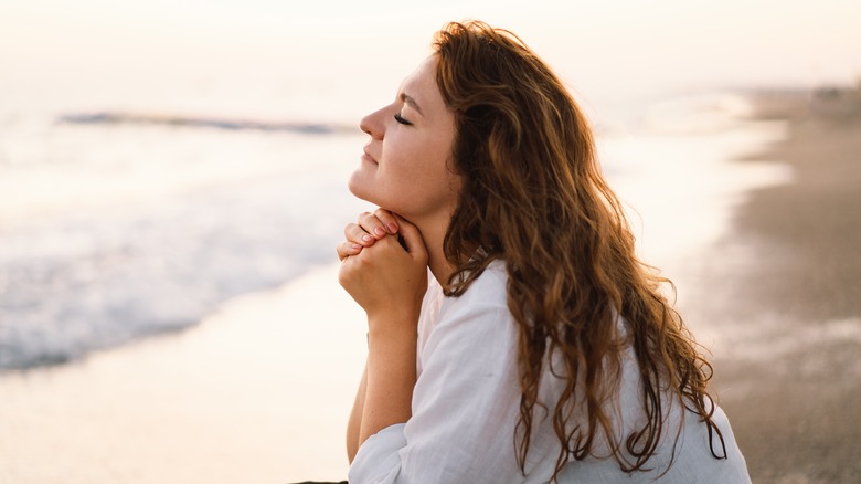 woman praying at beach