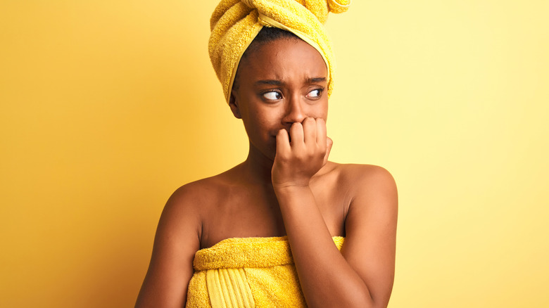 woman in yellow towel biting fingernails