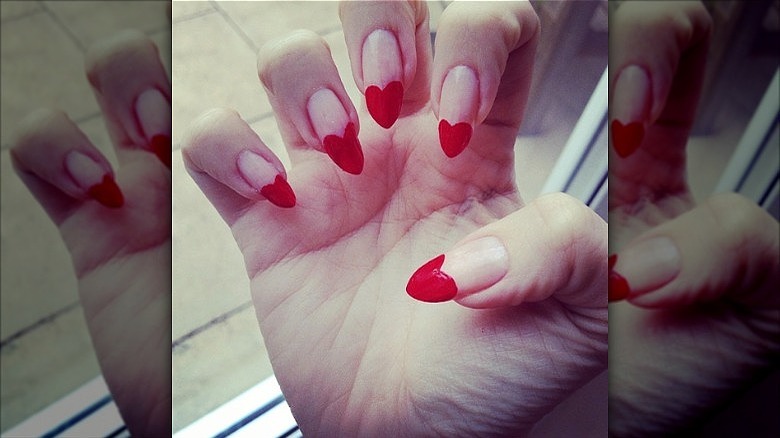 woman with red heart tip nails