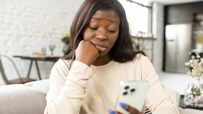 Woman looking at phone in disgust 