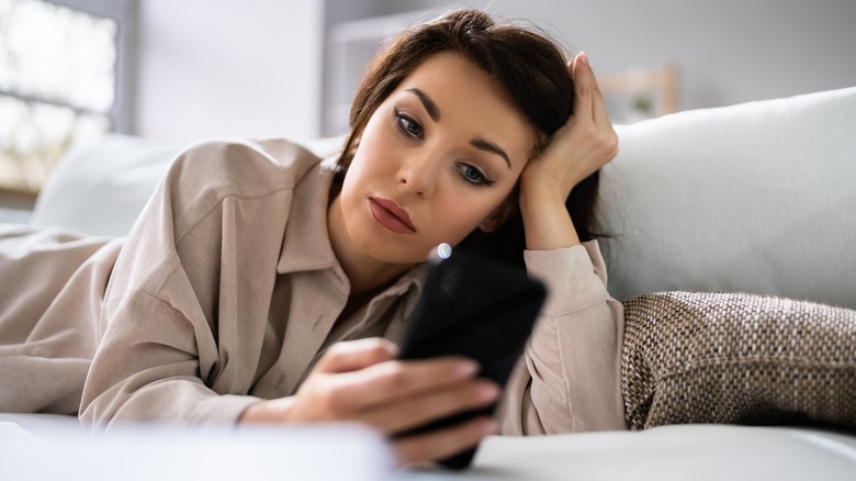 Woman looking at phone sad