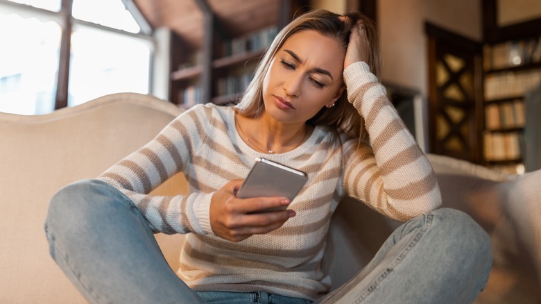 Woman looking sad holding phone 