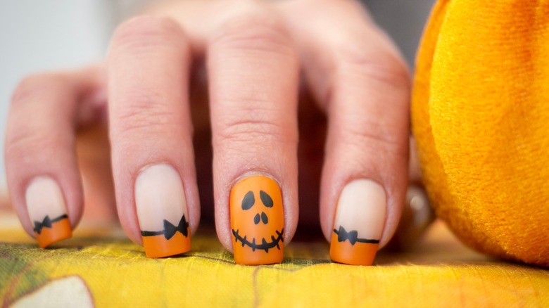 hand with pumpkin french manicure